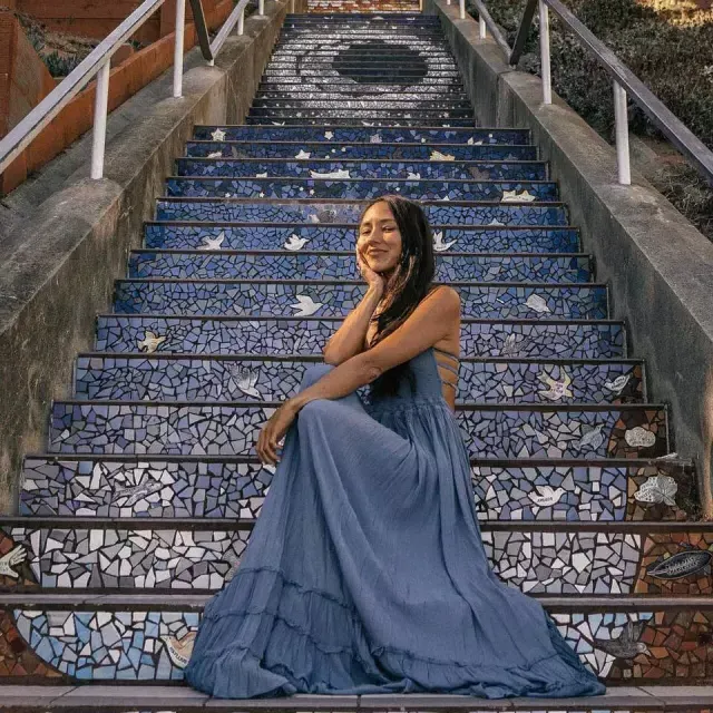 A woman poses sitting on the 16th Avenue tiled stairs in the Sunset neighborhood of San Francisco.
